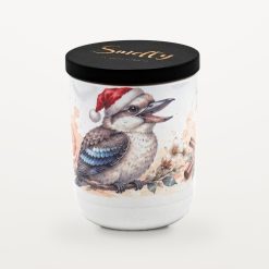 Smelty Christmas candle in a white ceramic jar with a black wooden lid and gold Smelty logo, printed with a laughing kookaburra in a Santa hat perched on a branch among white blossoms, cinnamon sticks and a soft watercolour wash of orange slices.